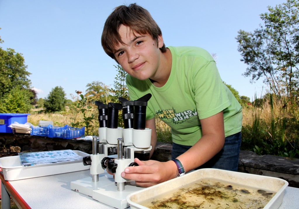 Young man looks through microscope at creatures he has found in the pond